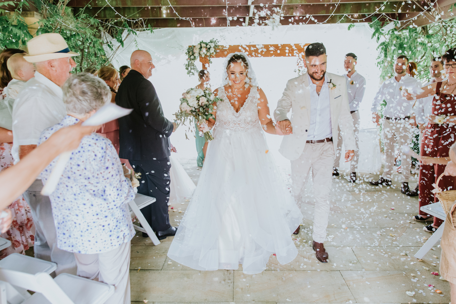 Sam and Jeff's wedding celebration as the bride walks through a shower of confetti with family and friends in Sydney